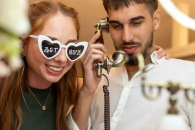 Jókedvű pár a ReCall telefonnál, a lány szív alakú, a pár monogramjával feliratozott szemüvegben